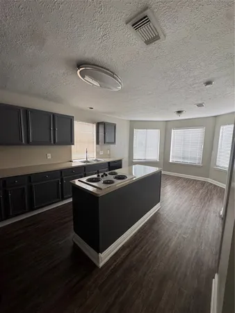 a kitchen with a stove wooden floor and cabinets