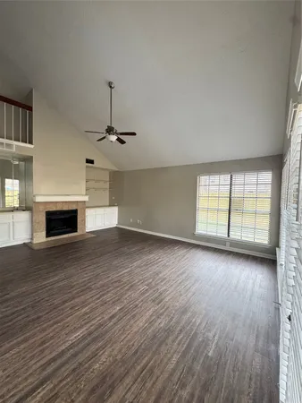 an empty room with wooden floor fireplace and windows