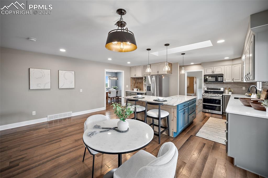 2304 Lazy R Lane Colorado Springs, CO 80915 - Photo 13 of 49 a kitchen with stainless steel appliances kitchen island granite countertop a table and chairs in it