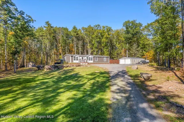 a front view of a house with a yard garage and a tree