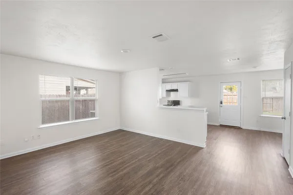 an empty room with wooden floor and windows