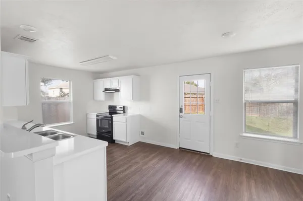 a view of a kitchen with wooden floor and electronic appliances
