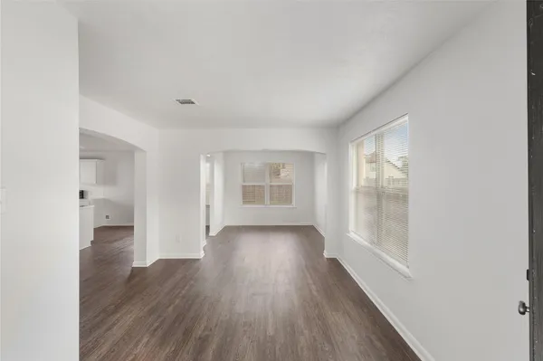 a view of an empty room with wooden floor and a window