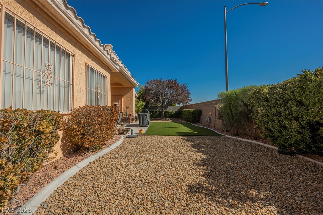 5494 Pine Ranch Street Las Vegas, NV 89113 - Photo 10 of 54 A well-maintained backyard featuring artificial turf and a covered patio for outdoor enjoyment.