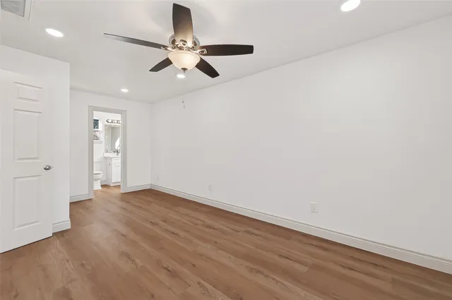 an empty room with wooden floor fan and windows