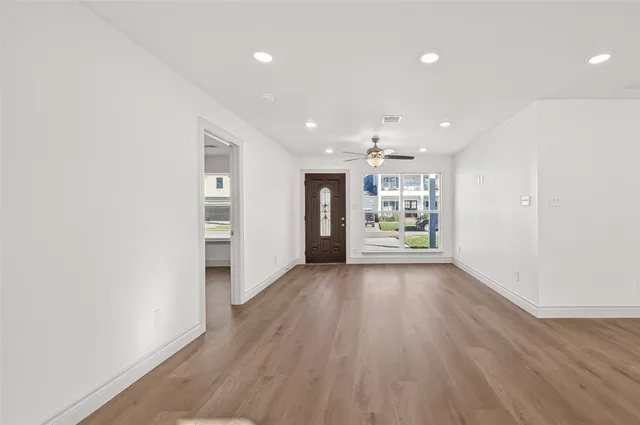 a view of a big room with wooden floor and windows