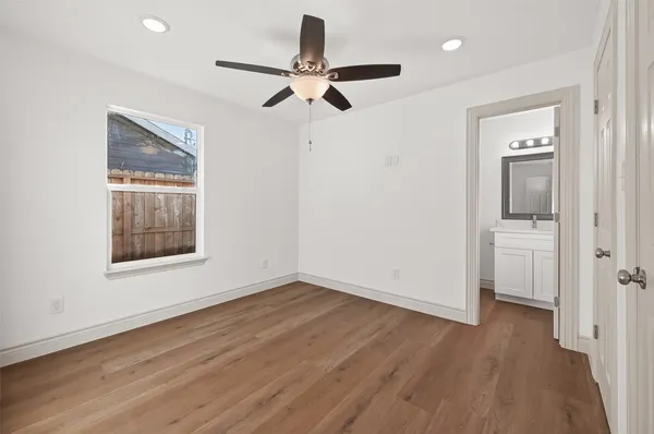 a view of empty room with wooden floor and fan
