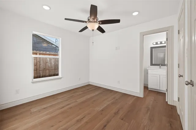a view of empty room with wooden floor and fan