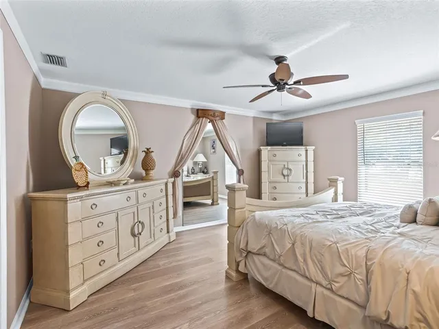 a bedroom with a bed a chandelier and dresser