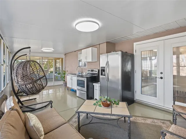 a living room with furniture a large window and stainless steel appliances