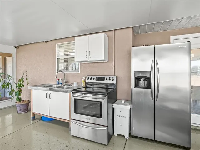a kitchen with stainless steel appliances white cabinets a sink and a refrigerator