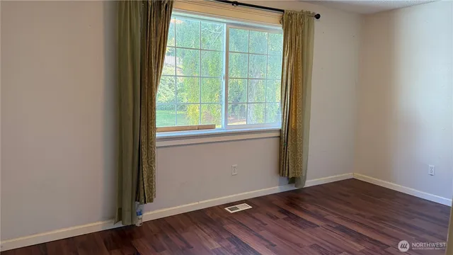 a view of a room that has wooden floor and a window