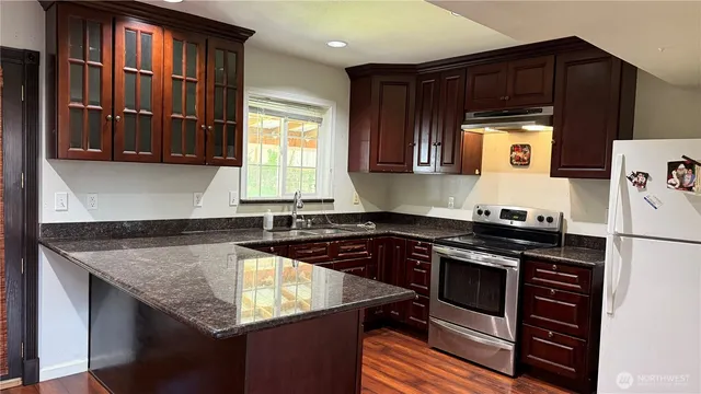 a kitchen with granite countertop a stove a sink and a microwave