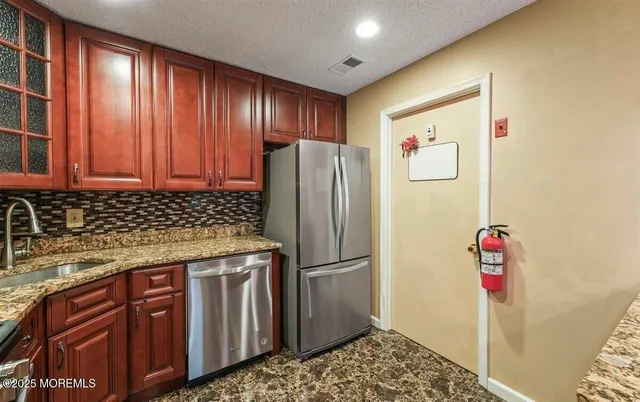 a kitchen with stainless steel appliances granite countertop a refrigerator and a sink