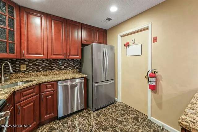 a kitchen with stainless steel appliances granite countertop a refrigerator and a sink
