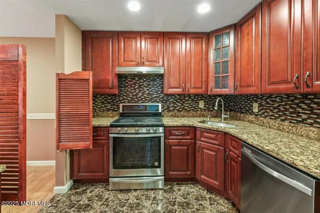 a kitchen with stainless steel appliances granite countertop wooden cabinets a sink and a stove