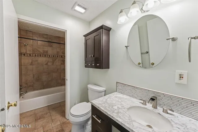 a bathroom with a granite countertop toilet a sink and a mirror