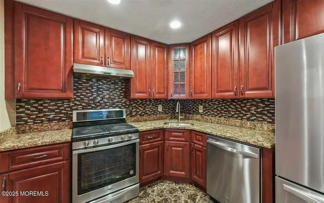 a kitchen with granite countertop cabinets stainless steel appliances and a counter space
