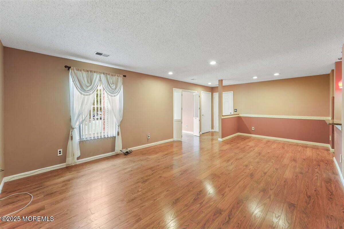19 Augusta Court, Unit 8 Freehold, NJ 07728 - Photo 9 of 27 a view of an empty room with wooden floor and a window