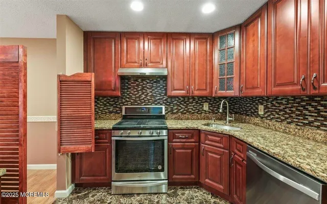 a kitchen with stainless steel appliances granite countertop wooden cabinets and a stove top oven