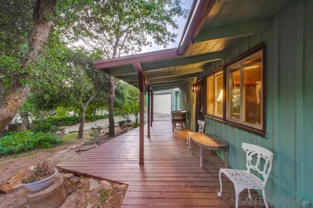 a view of a patio with table and chairs with wooden floor and fence
