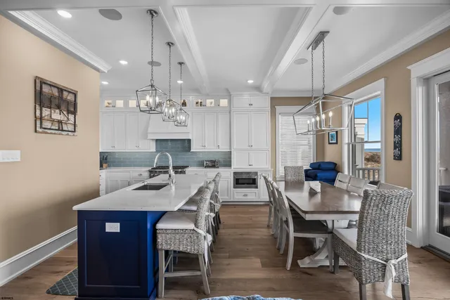 a kitchen with stainless steel appliances granite countertop a sink dishwasher a stove and a dining table with wooden floor