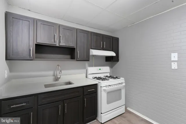 a kitchen with white cabinets a sink stove and microwave