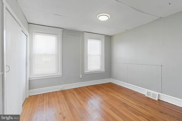 an empty room with wooden floor and windows