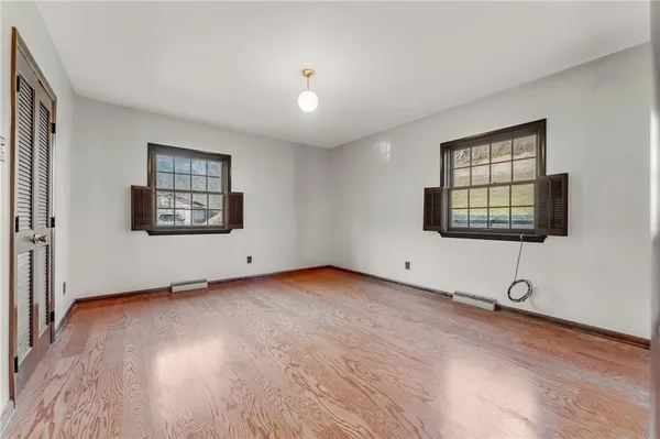 an empty room with windows and chandelier fan