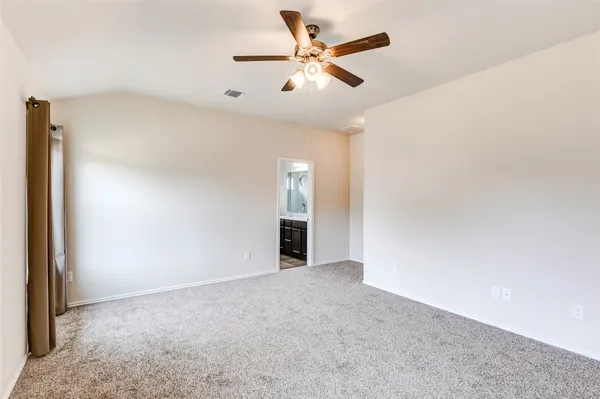an empty room with chandelier fan and windows