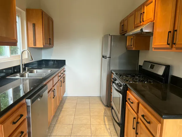 a kitchen with granite countertop a sink stove and refrigerator