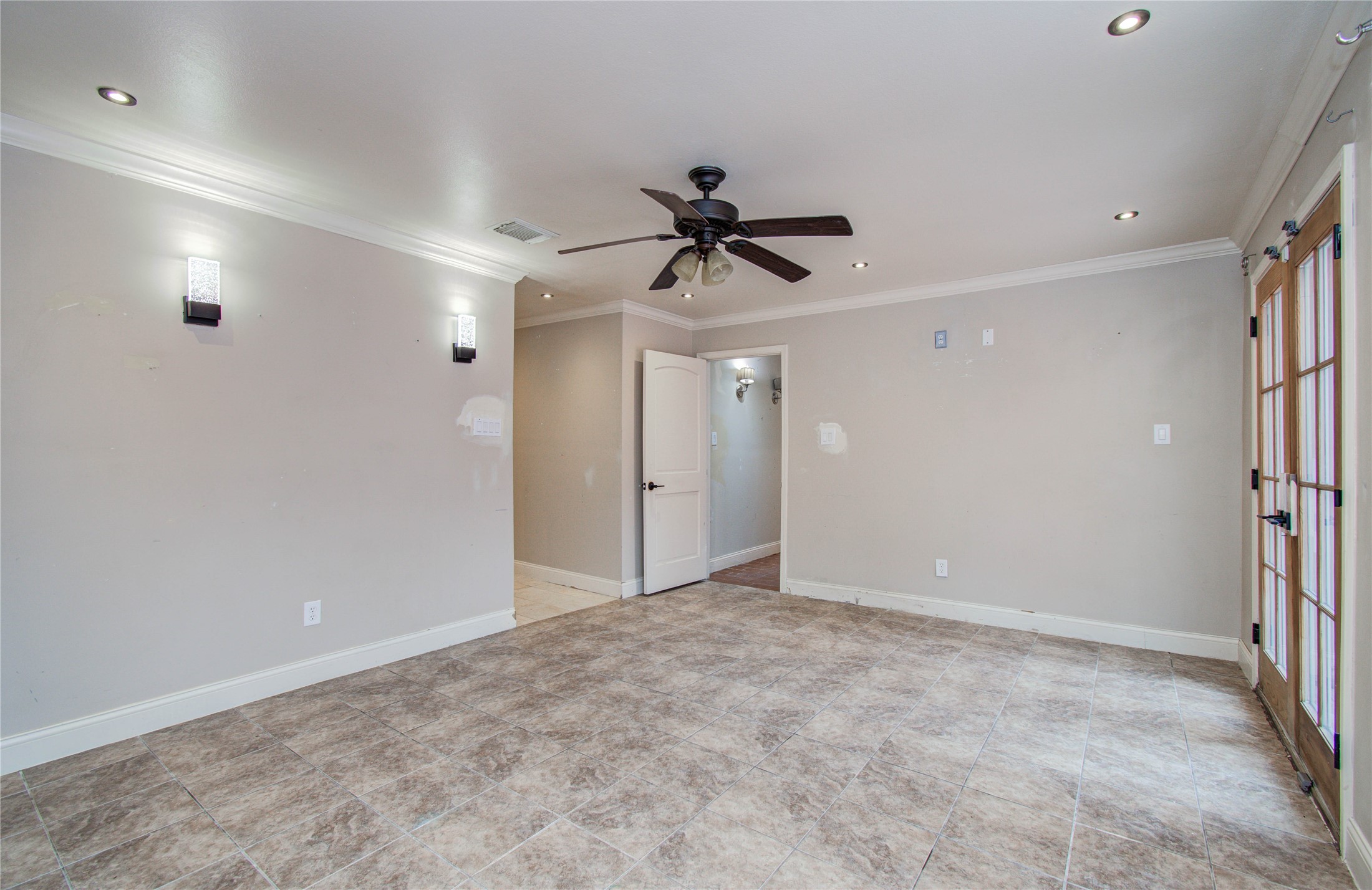2006 Waterelm Drive Houston, TX 77084 - Photo 21 of 27 Experience modern comfort in this spacious primary bedroom, featuring elegant tiled flooring, soft recessed lighting, and stylish French doors that flood the room with natural light.