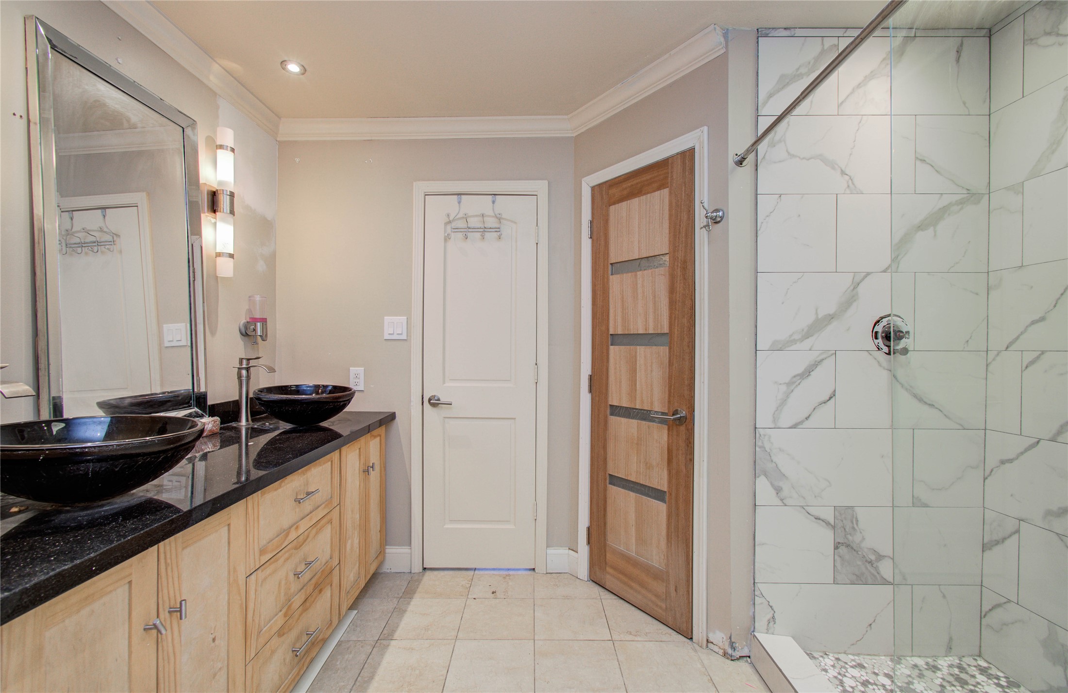 2006 Waterelm Drive Houston, TX 77084 - Photo 22 of 27 This elegant primary bathroom boasts a modern design with dual vessel sinks, sleek black granite countertops, and a spacious glass-enclosed shower with luxurious marble tile, creating a serene and stylish retreat.