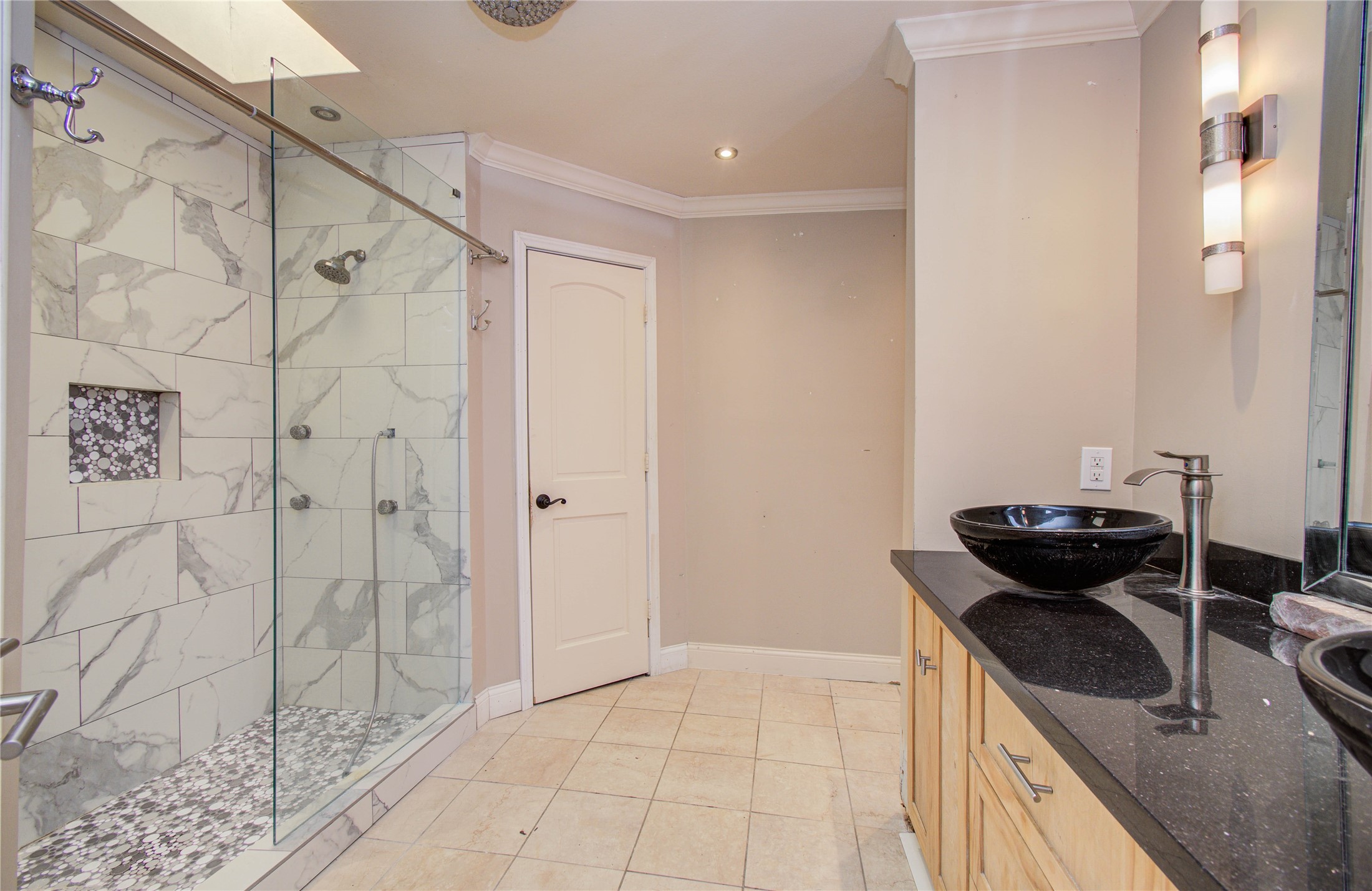 2006 Waterelm Drive Houston, TX 77084 - Photo 23 of 27 Escape to luxury in this elegant primary bathroom, featuring a spacious glass-enclosed shower with sleek marble tiles, modern vessel sinks atop a stylish vanity, and warm ambient lighting for a spa-like retreat at home.