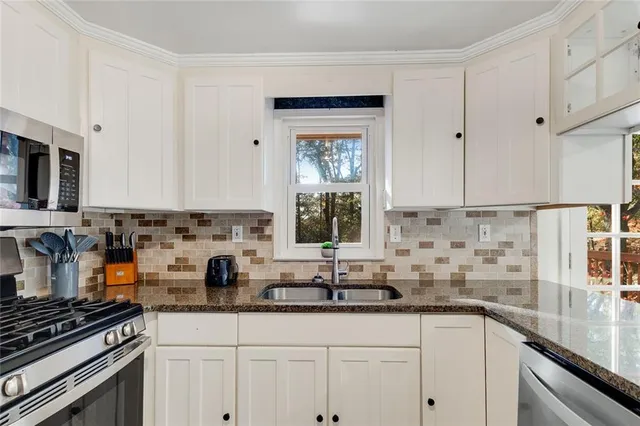 a kitchen with granite countertop a sink a stove and cabinets