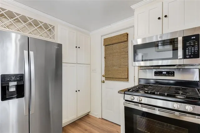 a kitchen with stainless steel appliances a refrigerator a stove and white cabinets