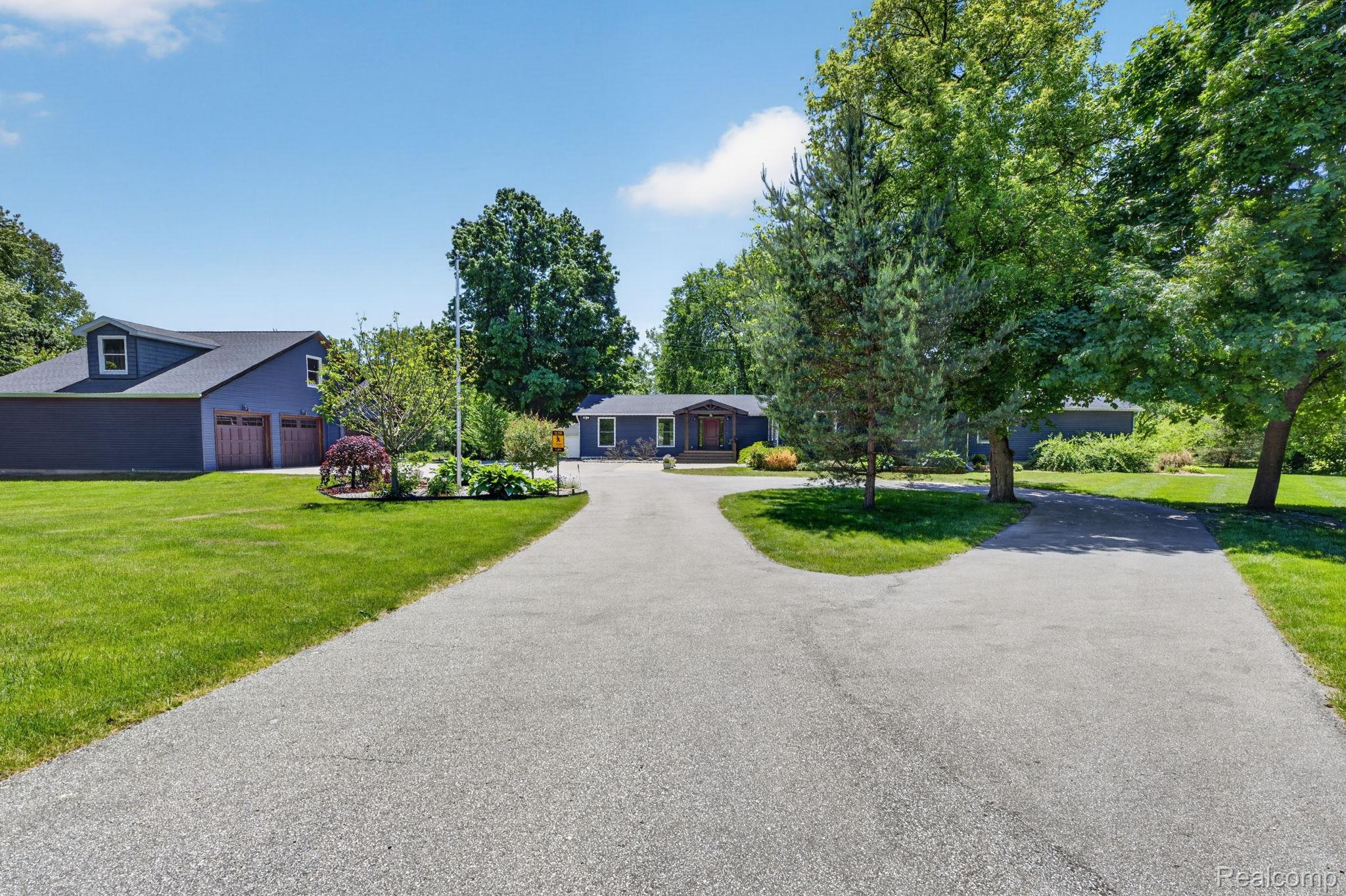 9353 Hill Road Swartz Creek, MI 48473 - Photo 2 of 98 Spacious property featuring a main residence with a covered entry, a two-car garage with dormer windows, and a detached outbuilding