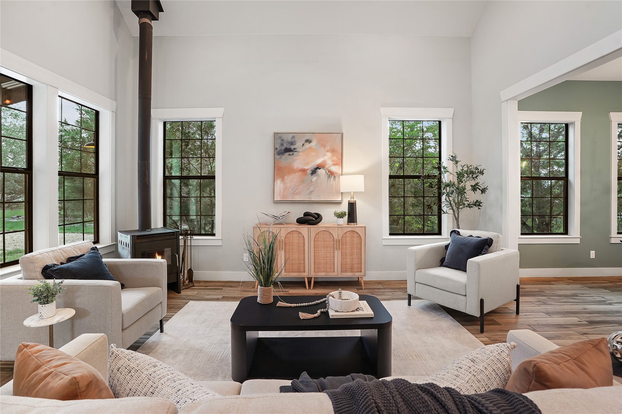 786 Beauchamp Road Dripping Springs, TX 78620 - Photo 11 of 40 Living area featuring high ceilings, a wood-burning stove with a stovepipe, and large windows with black frames