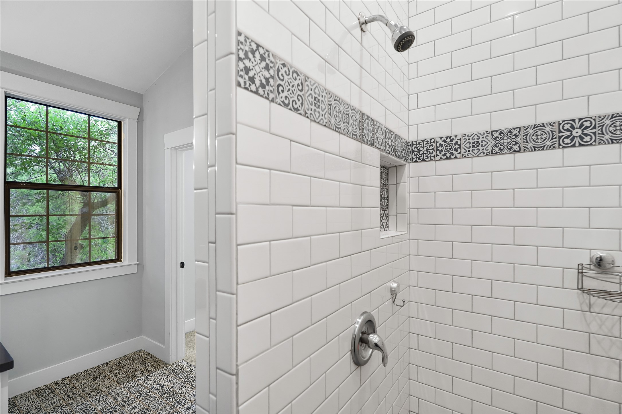786 Beauchamp Road Dripping Springs, TX 78620 - Photo 18 of 40 The bathroom features a shower with white subway tiles and a decorative patterned tile accent band, a built-in shower niche, and a window with a grid pattern