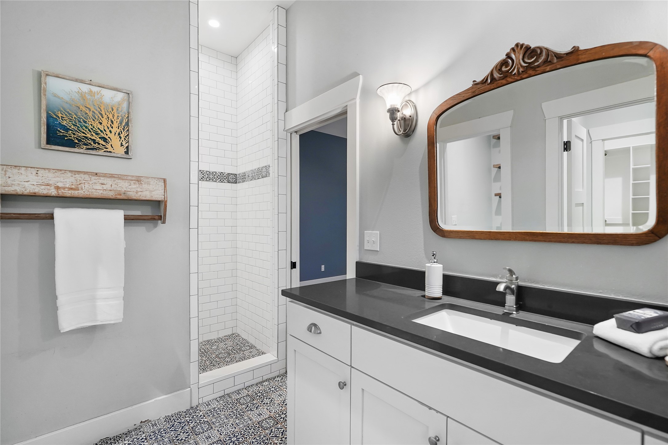 786 Beauchamp Road Dripping Springs, TX 78620 - Photo 19 of 40 This bathroom features a walk-in shower with white subway tile and a patterned floor, and a vanity with white cabinetry, a dark countertop, and an undermount sink