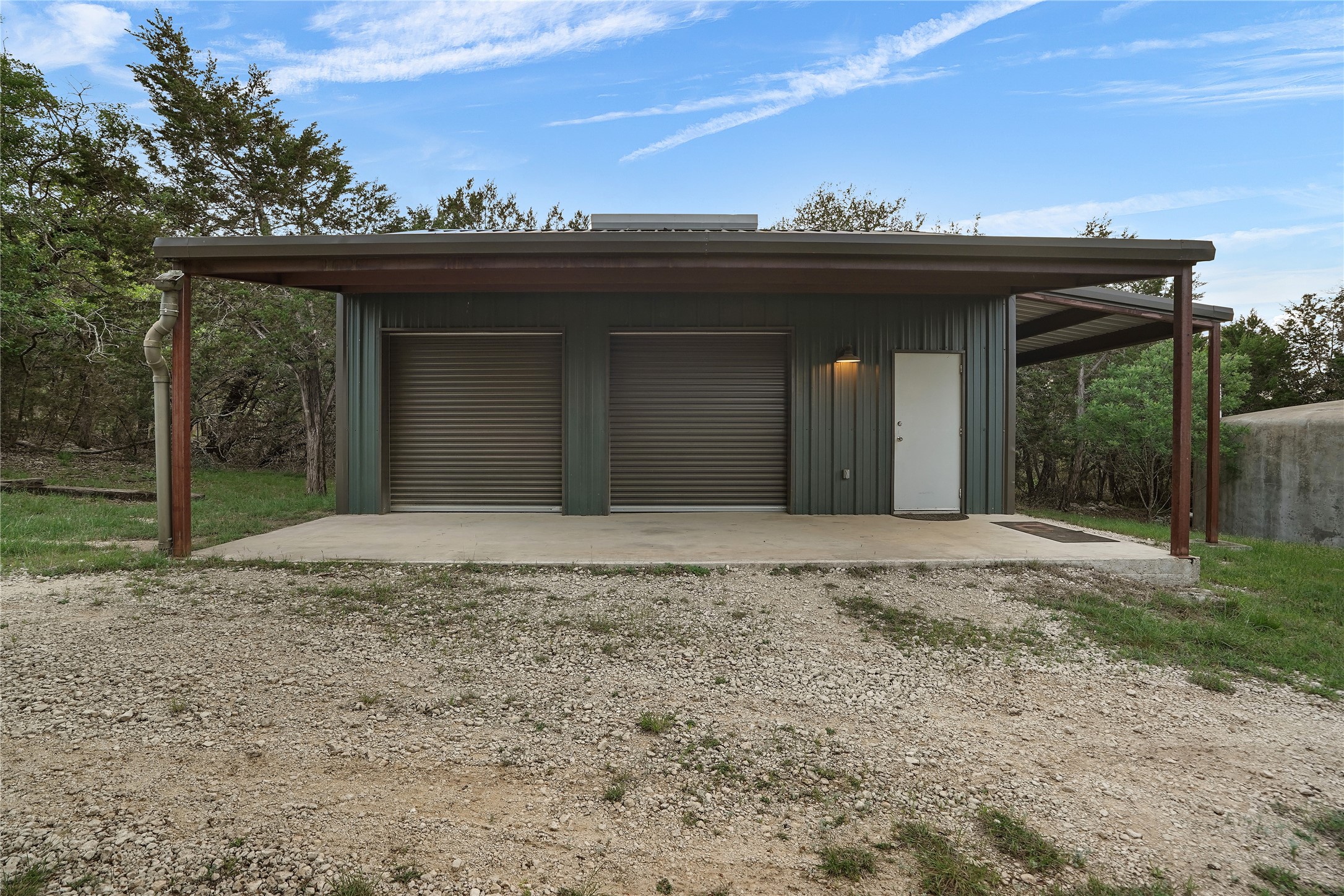 786 Beauchamp Road Dripping Springs, TX 78620 - Photo 29 of 40 Detached garage with two roll-up doors, an exterior door, and an attached carport