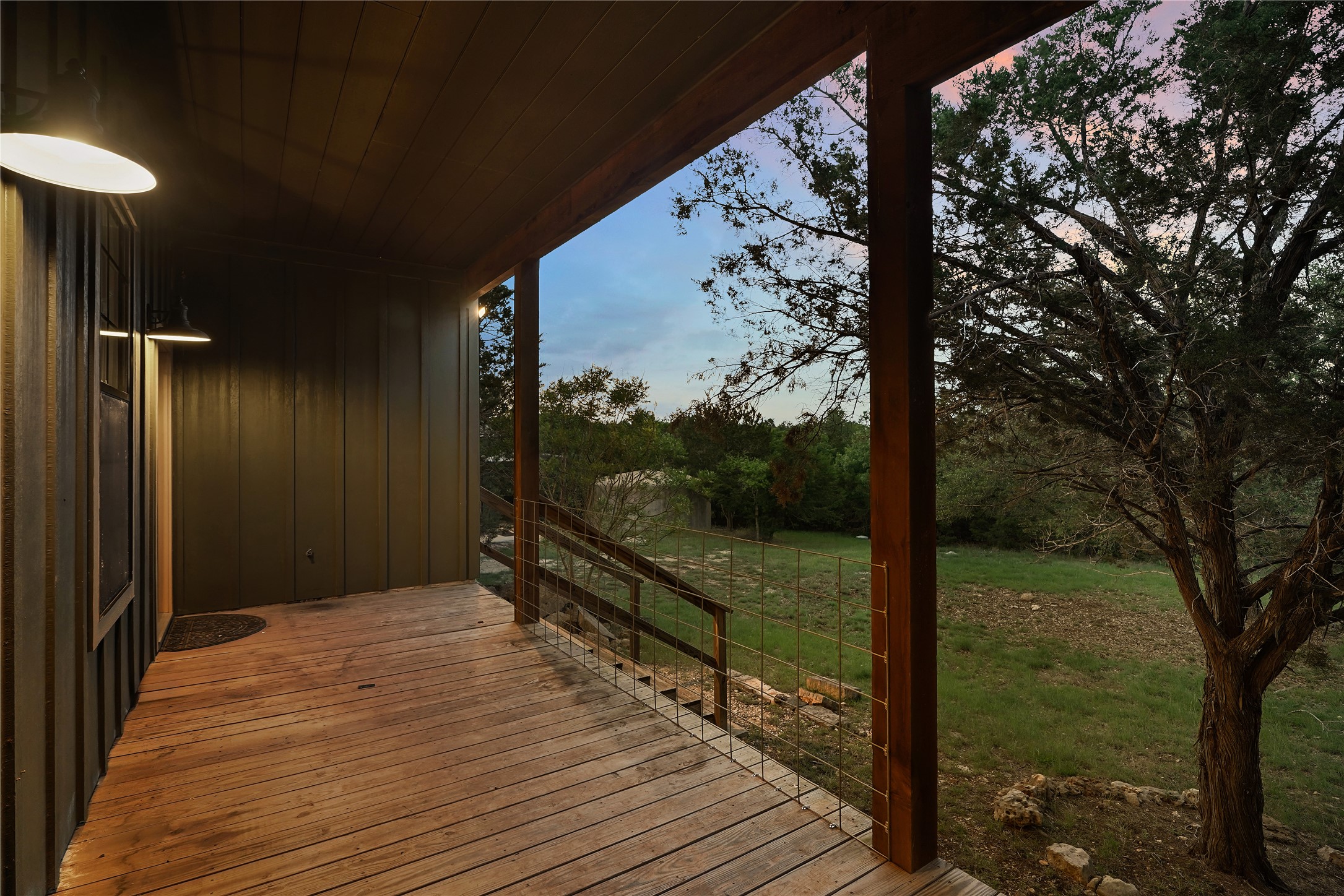 786 Beauchamp Road Dripping Springs, TX 78620 - Photo 35 of 40 The property features a spacious wooden deck with a railing and an exterior light fixture, providing outdoor access