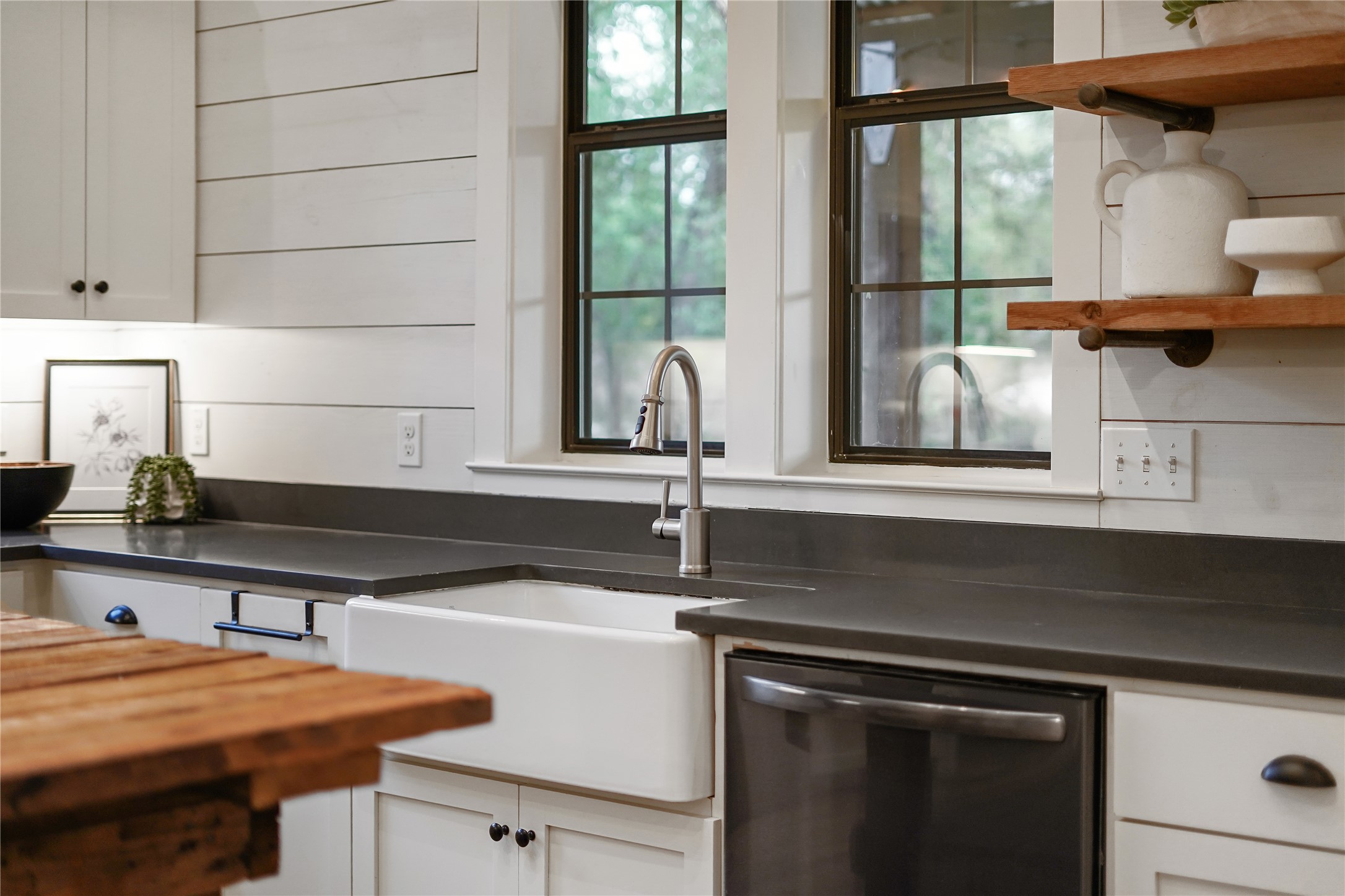 786 Beauchamp Road Dripping Springs, TX 78620 - Photo 6 of 40 The kitchen features white shaker style cabinetry with dark hardware, dark countertops, a white farmhouse sink with a gooseneck faucet, and stainless steel appliances