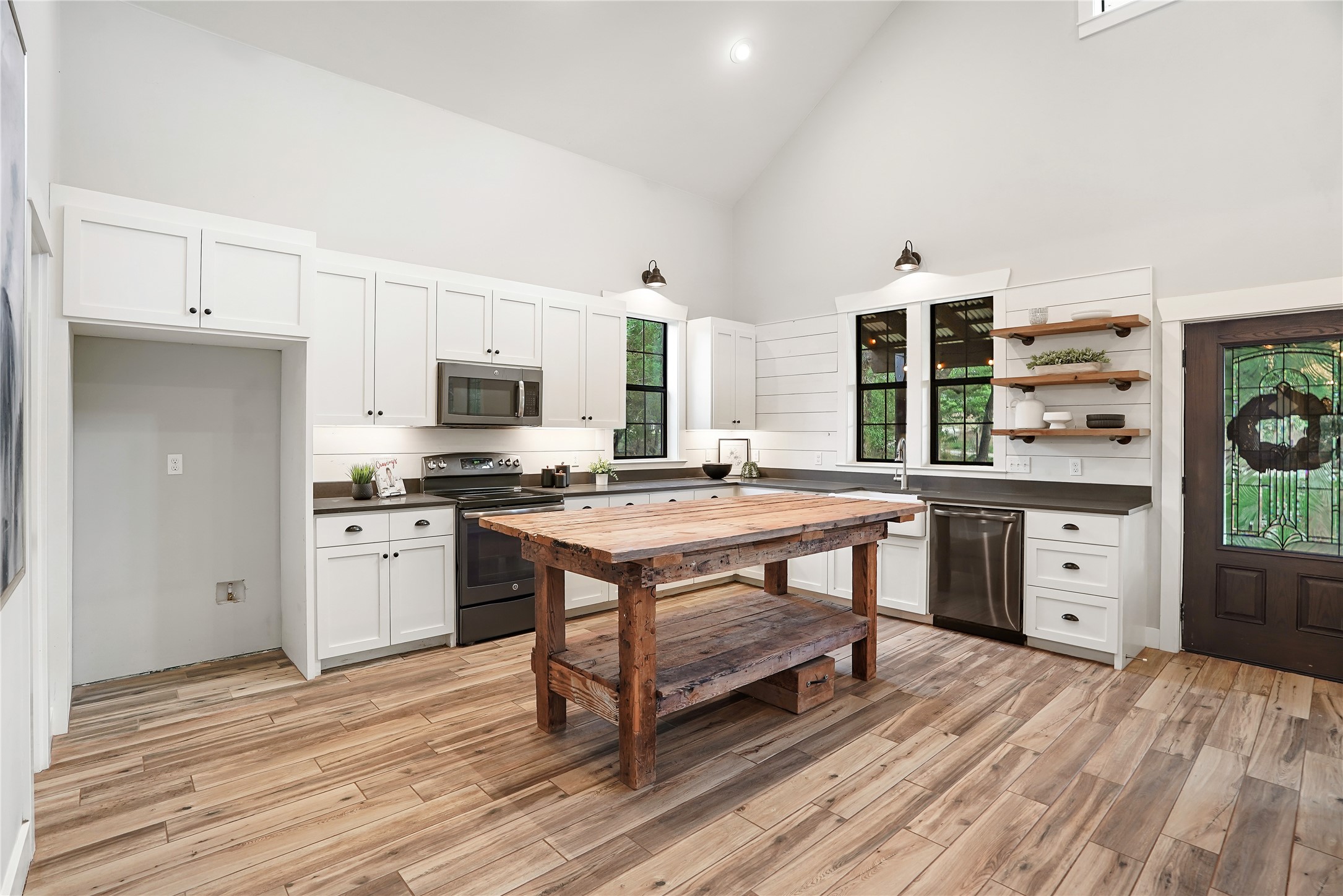 786 Beauchamp Road Dripping Springs, TX 78620 - Photo 7 of 40 The kitchen features a vaulted ceiling, wood-look flooring, white cabinetry, dark countertops, and a wooden island