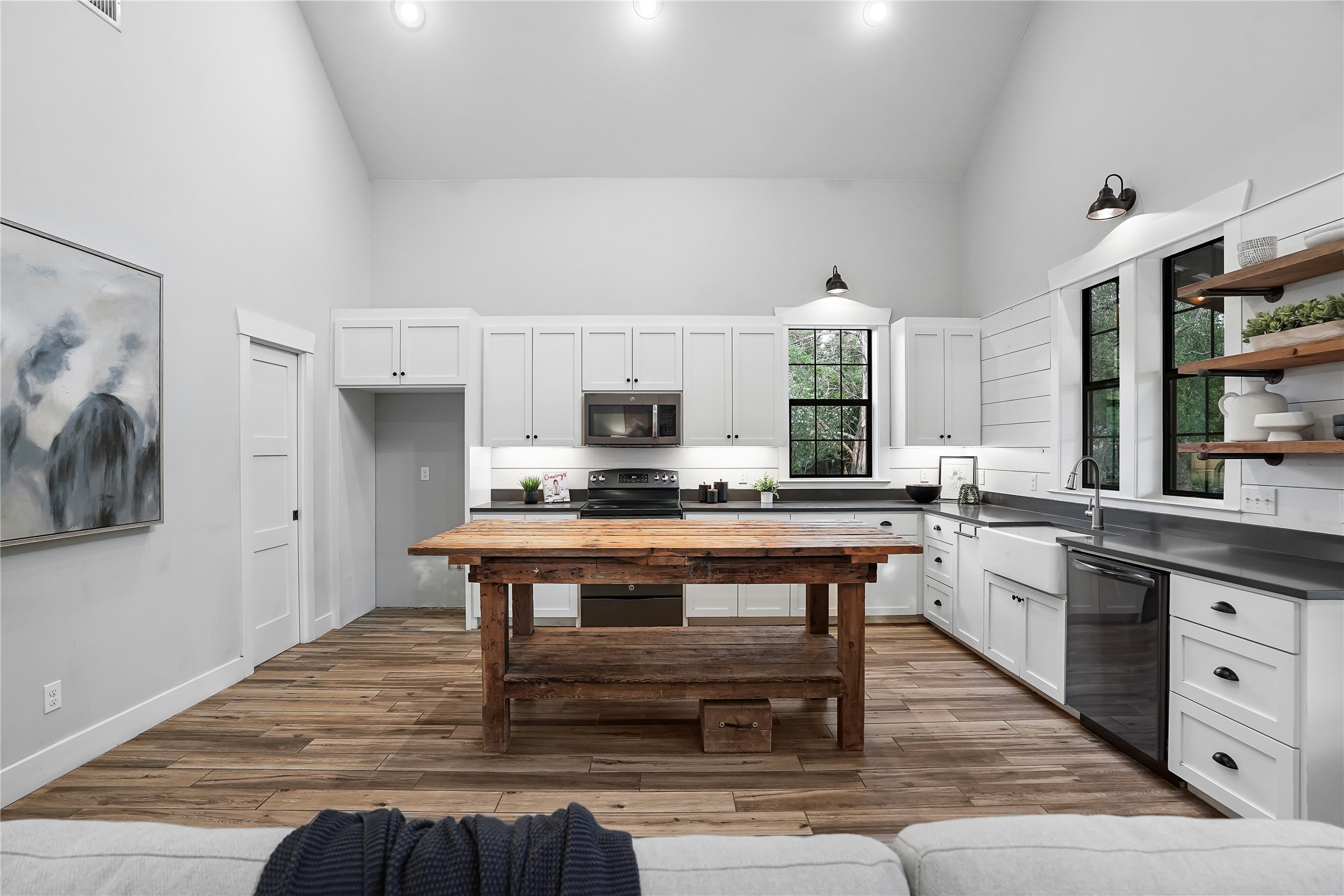 786 Beauchamp Road Dripping Springs, TX 78620 - Photo 8 of 40 The kitchen features high ceilings, wood plank flooring, a rustic wooden island, white cabinetry, and stainless steel appliances