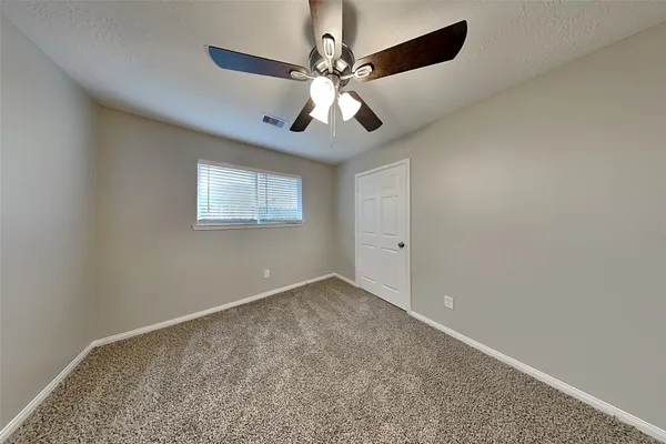 an empty room with windows and chandelier fan