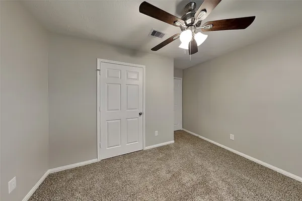 an empty room with closet and a chandelier fan