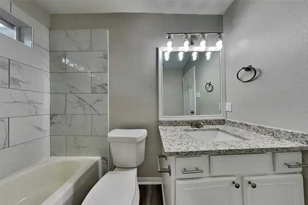a bathroom with a granite countertop sink a toilet and bathtub