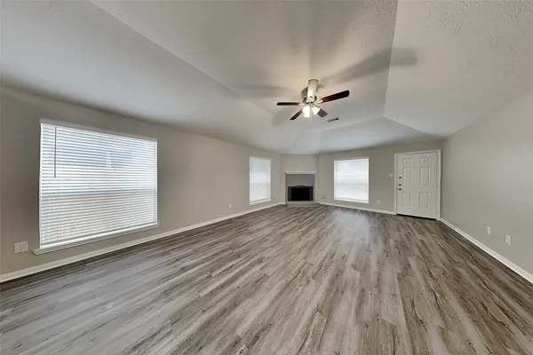 a view of an empty room with a window and wooden floor