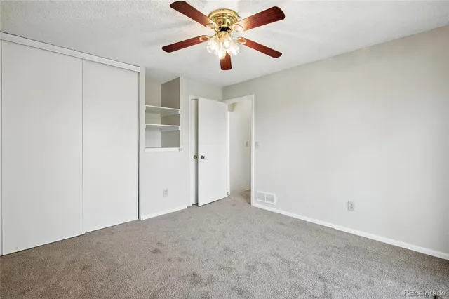 an empty room with closet and a ceiling fan